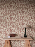 Tree of Life wallpaper by Sandberg in rust-red trailing fruit branches on cream, styled above a timber console with rattan lamp