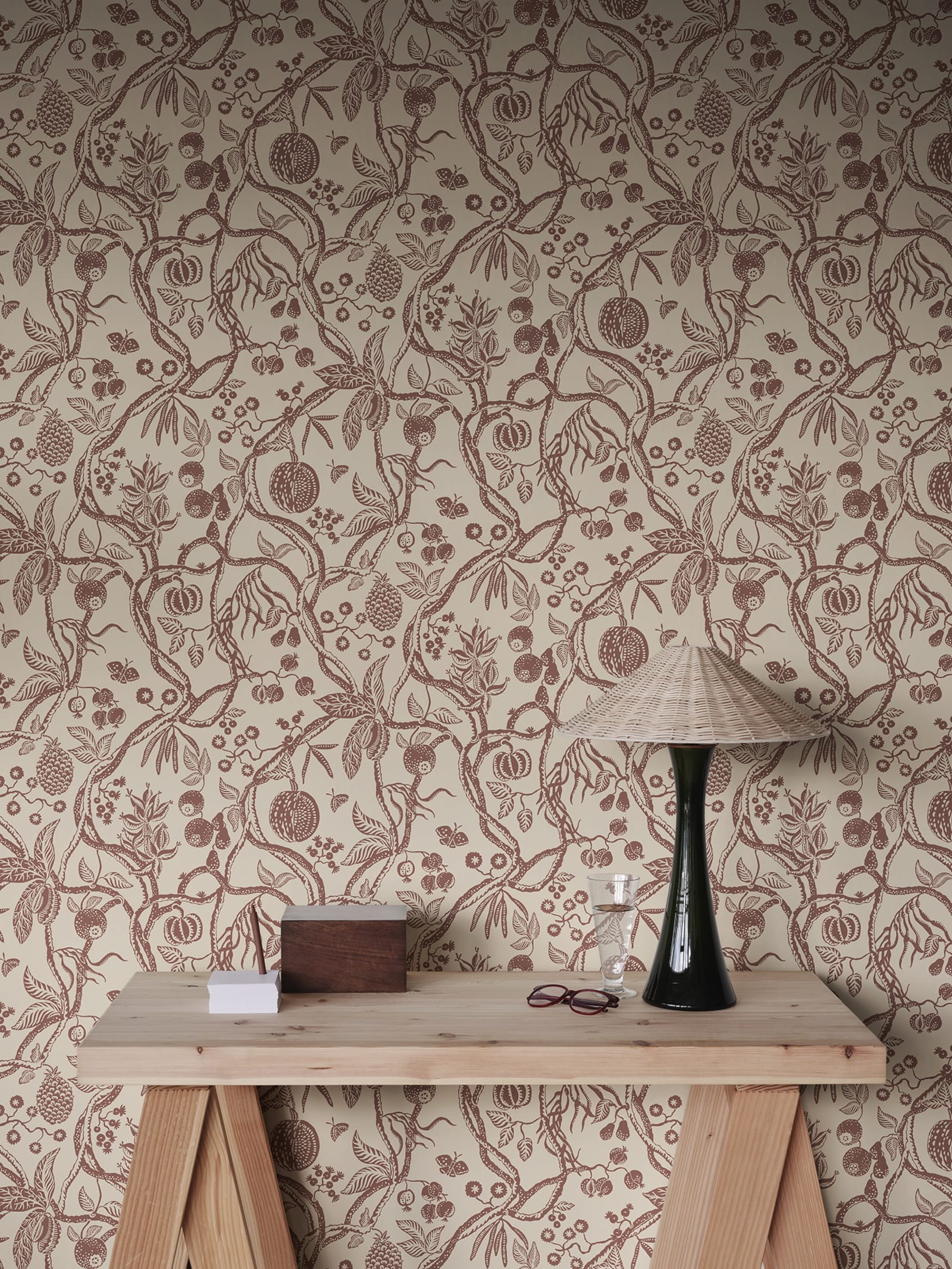 Tree of Life wallpaper by Sandberg in rust-red trailing fruit branches on cream, styled above a timber console with rattan lamp