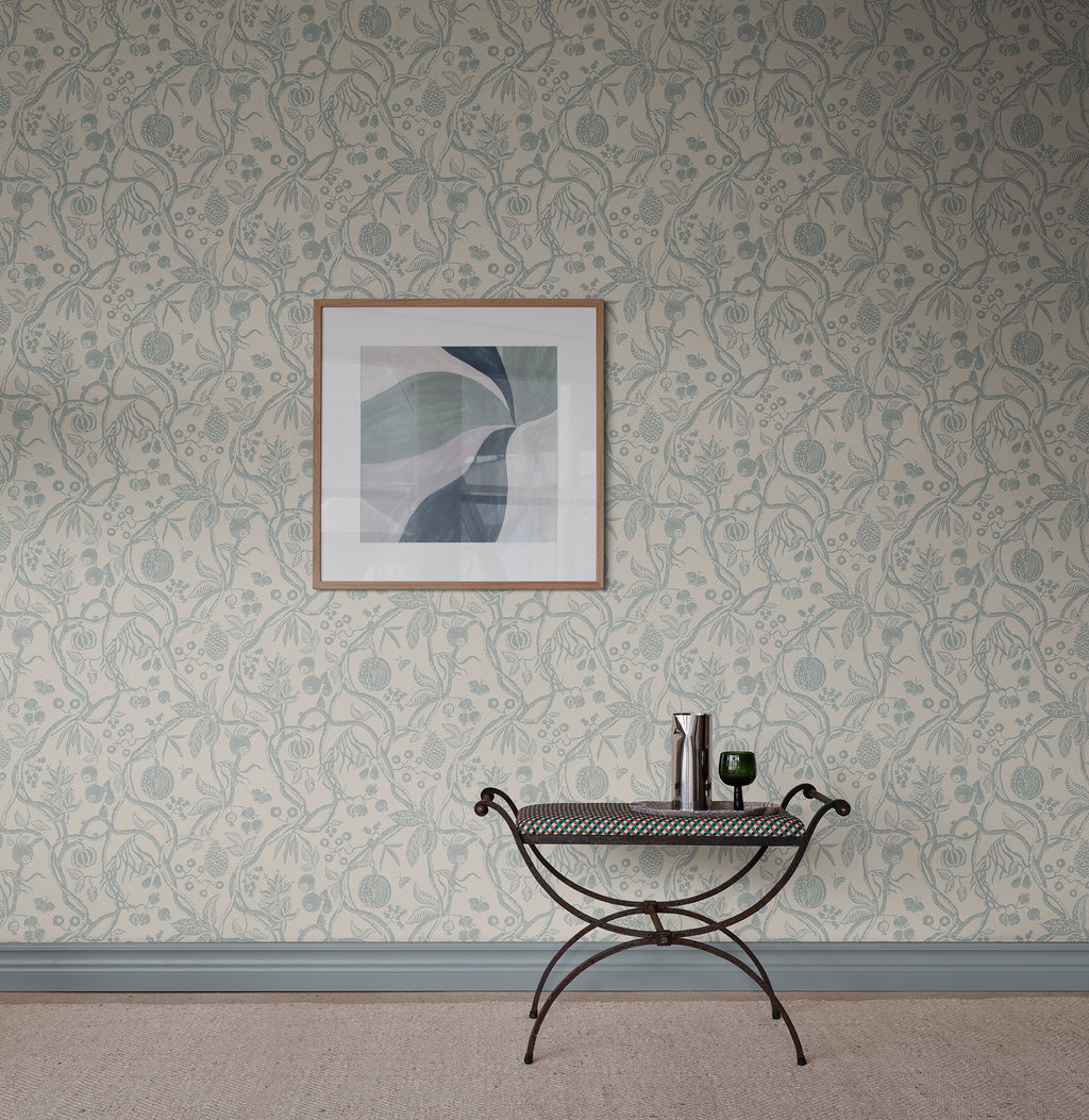 Tree of Life wallpaper by Sandberg in soft blue-grey, styled on a wall with framed abstract art above an iron bench