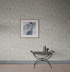 Tree of Life wallpaper by Sandberg in soft blue-grey, styled on a wall with framed abstract art above an iron bench