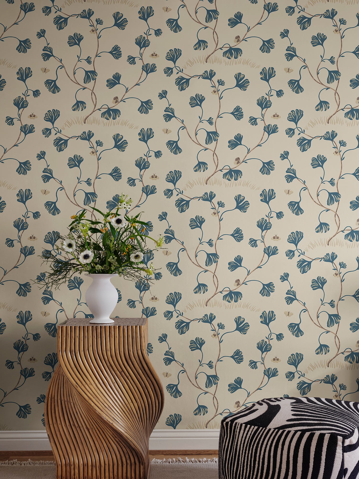 Ebba wallpaper by Sandberg in cream behind a sculptural timber side table topped with a vase of wildflowers