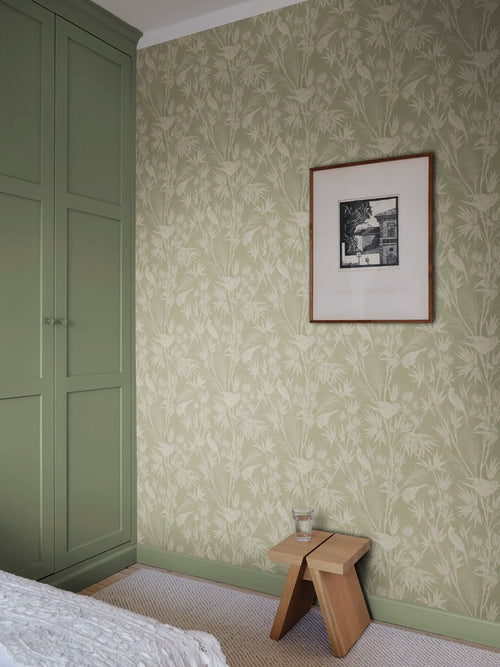 Celeste wallpaper by Sandberg in sage green in a calm bedroom corner with a green wardrobe and framed print