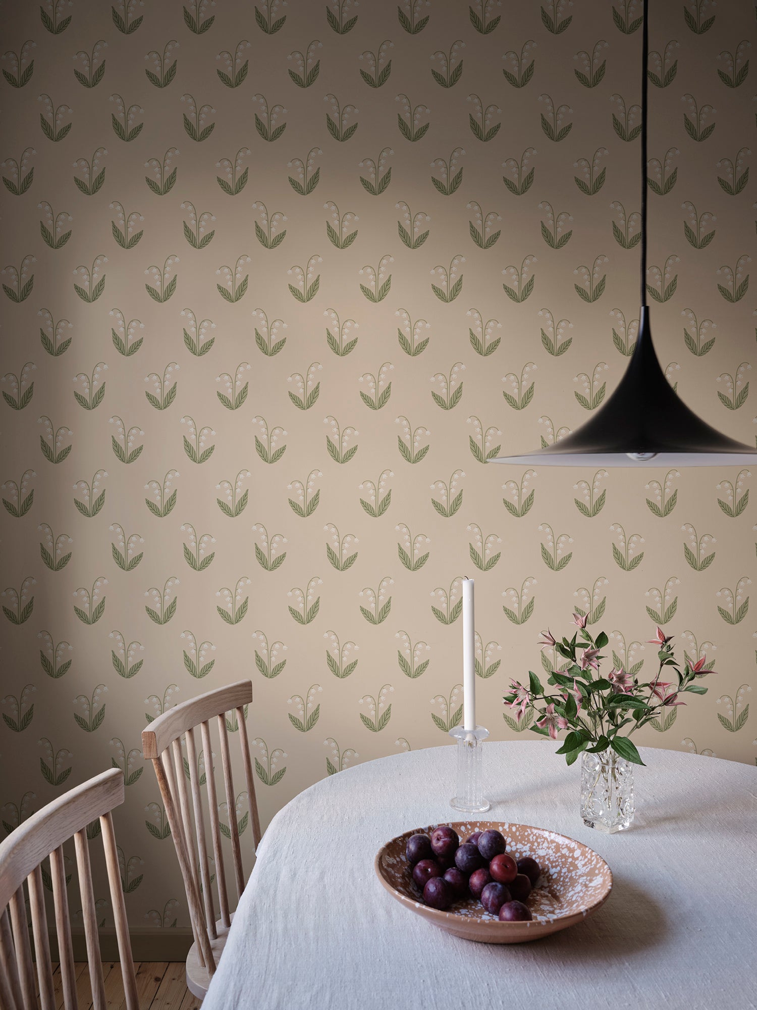 Lilly wallpaper by Sandberg in beige behind a dining table set with fruit, candle and fresh flowers