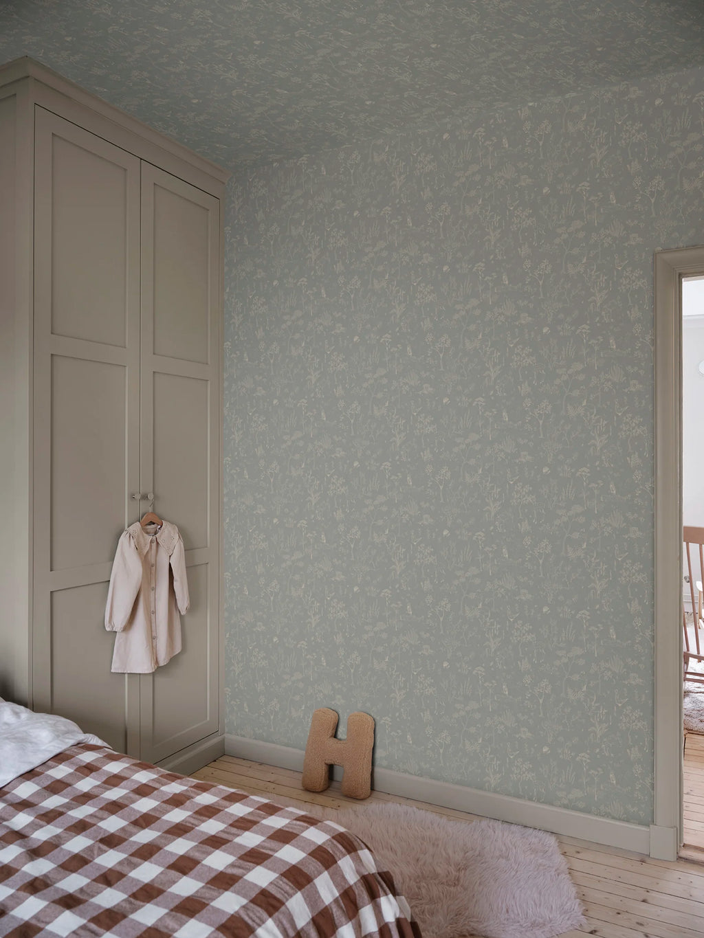 Hollie wallpaper by Sandberg in soft grey-green woodland print in a calm bedroom with panelled wardrobe
