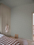Hollie wallpaper by Sandberg in soft grey-green woodland print in a calm bedroom with panelled wardrobe