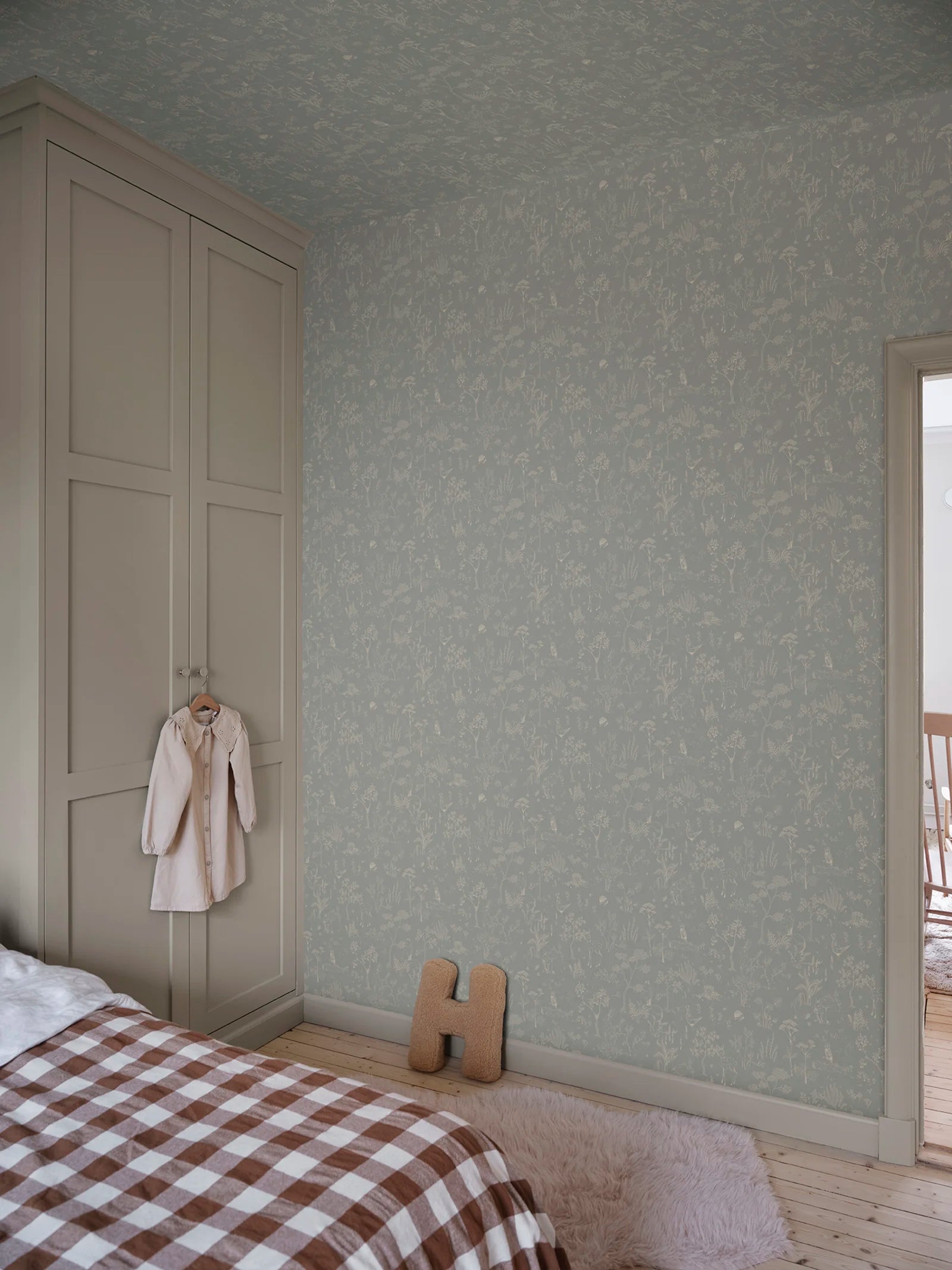 Hollie wallpaper by Sandberg in soft grey-green woodland print in a calm bedroom with panelled wardrobe