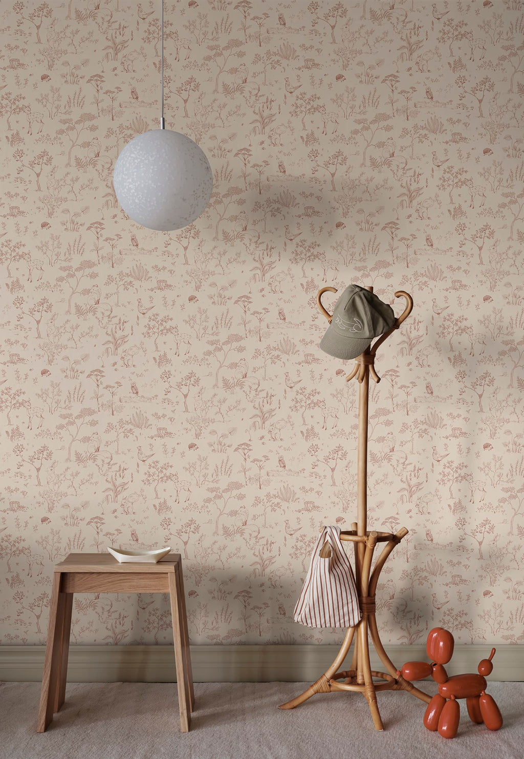 Hollie wallpaper by Sandberg in dusky pink woodland print in a hallway with wooden stool and rattan coat stand