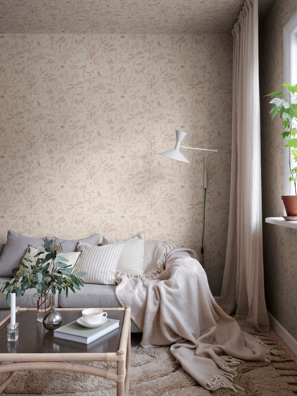 Hollie wallpaper by Sandberg in blush pink woodland print in a snug living room corner with grey sofa