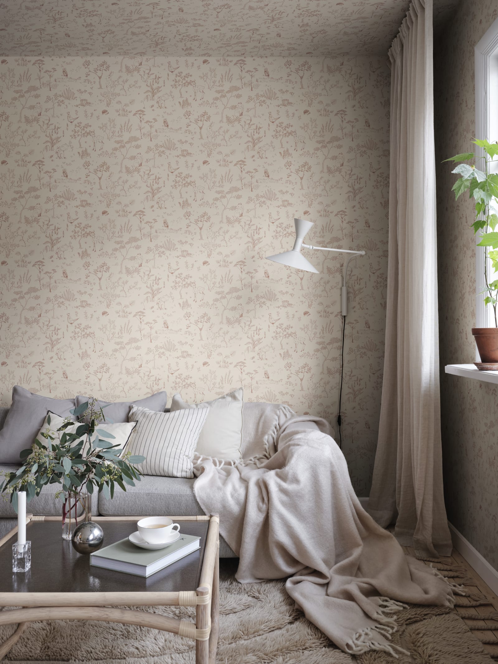 Hollie wallpaper by Sandberg in blush pink woodland print in a snug living room corner with grey sofa