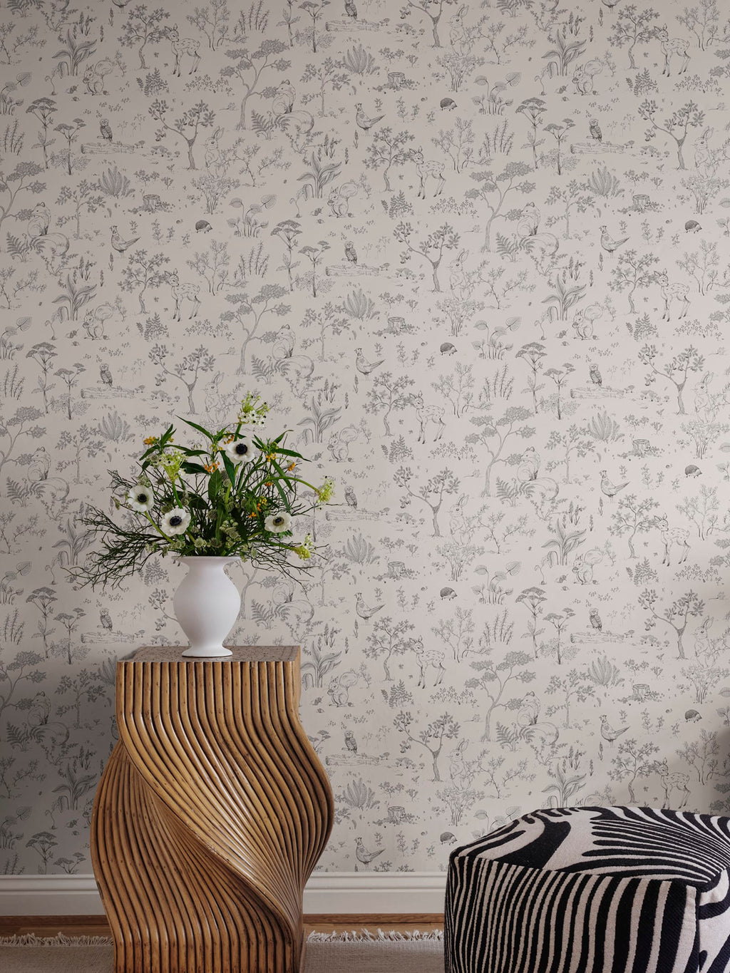 Hollie wallpaper by Sandberg in soft grey woodland print with a sculptural wooden side table and white vase