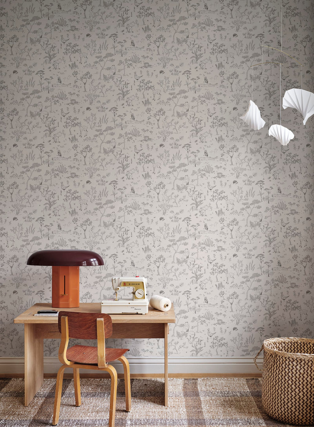 Hollie wallpaper by Sandberg in grey woodland print behind a childs desk with vintage sewing machine and lamp