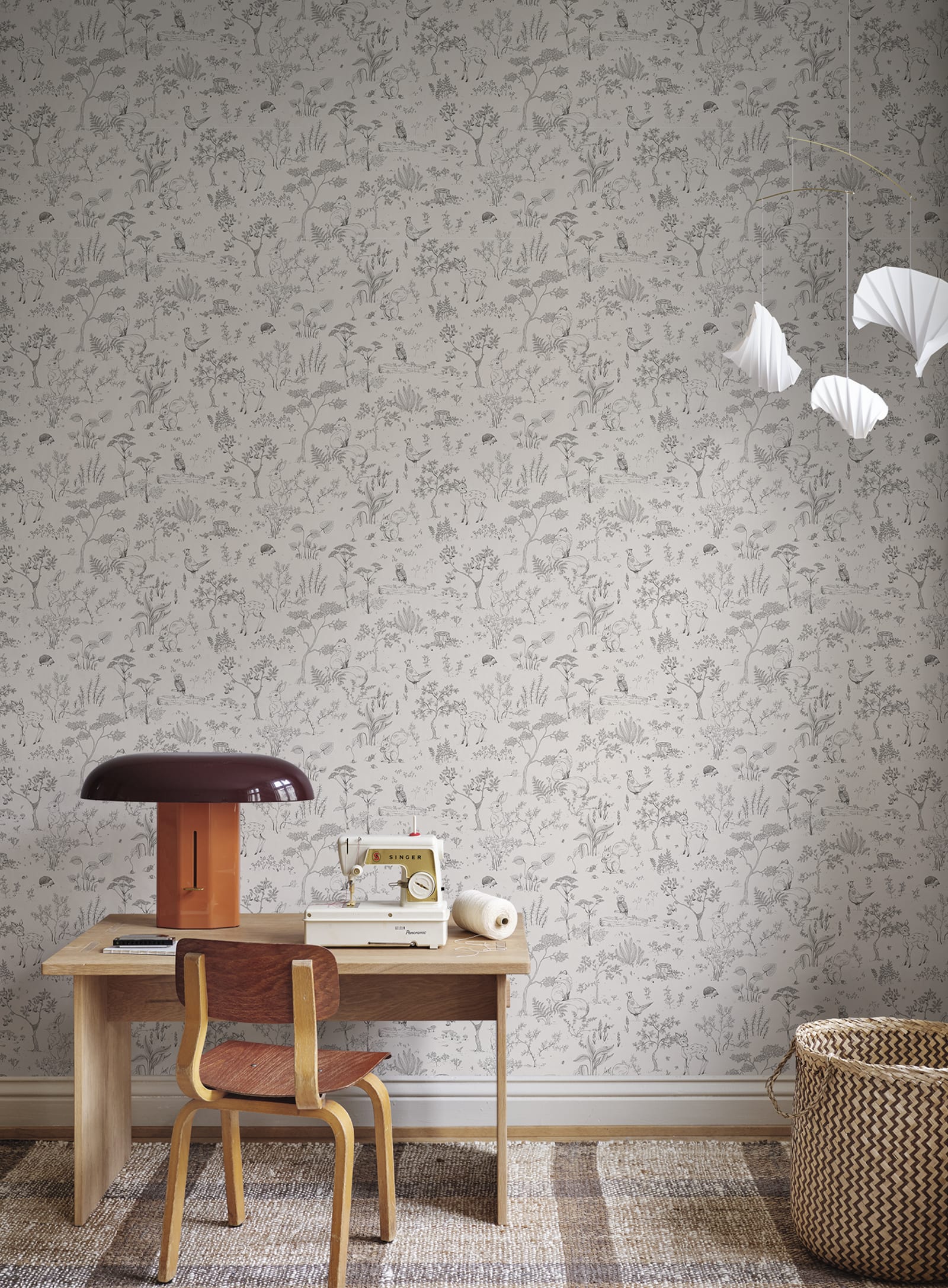 Hollie wallpaper by Sandberg in grey woodland print behind a childs desk with vintage sewing machine and lamp