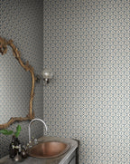 Elena blue floral wallpaper by Sandberg in a powder room, branch-framed mirror above a hammered copper basin and stone vanity