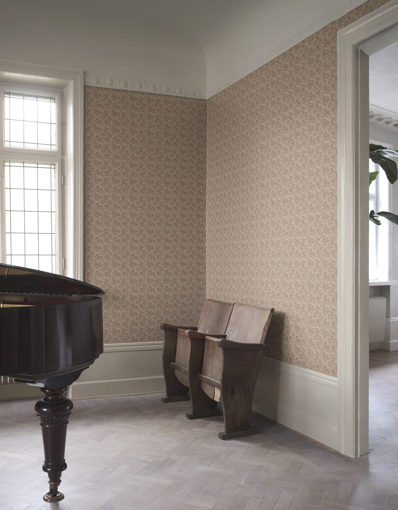 Coral wallpaper by Sandberg in clay tones, styled in a grand room with grand piano and antique wooden cinema seats