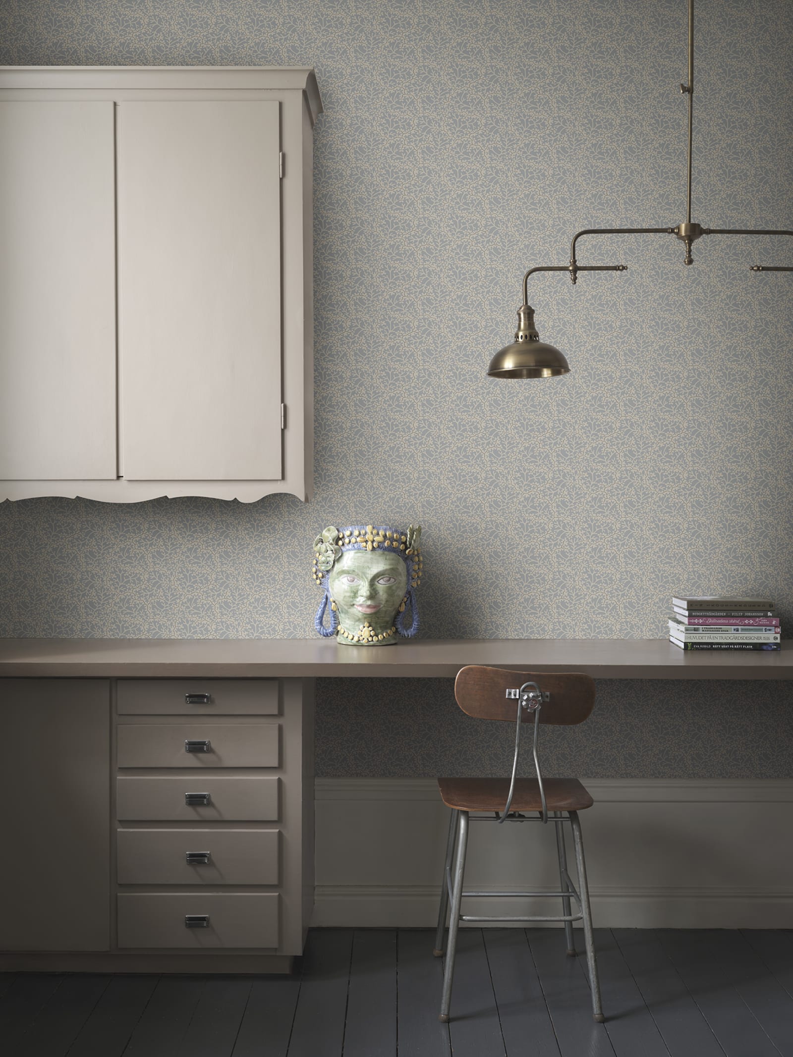 Coral wallpaper by Sandberg in blue-grey, styled in a home office with desk, brass lamp and ceramic head vase