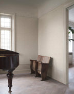 Mila wallpaper by Sandberg in tonal cream, styled in a refined room with a grand piano and antique theatre seats