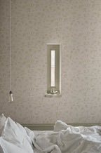 Mila wallpaper by Sandberg in sage on cream, styled in a bedroom with a slim recessed window and rumpled white bedding