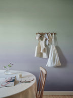 Skymning wall mural by Sandberg, green-to-lilac ombré sky styled in a dining nook with a peg rail and linen-draped table
