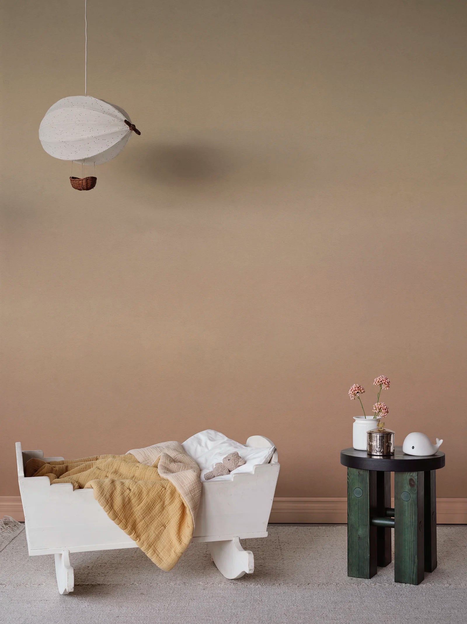 Skymning wall mural by Sandberg, cream-to-terracotta ombré sky styled in a nursery with a white cradle and balloon mobile