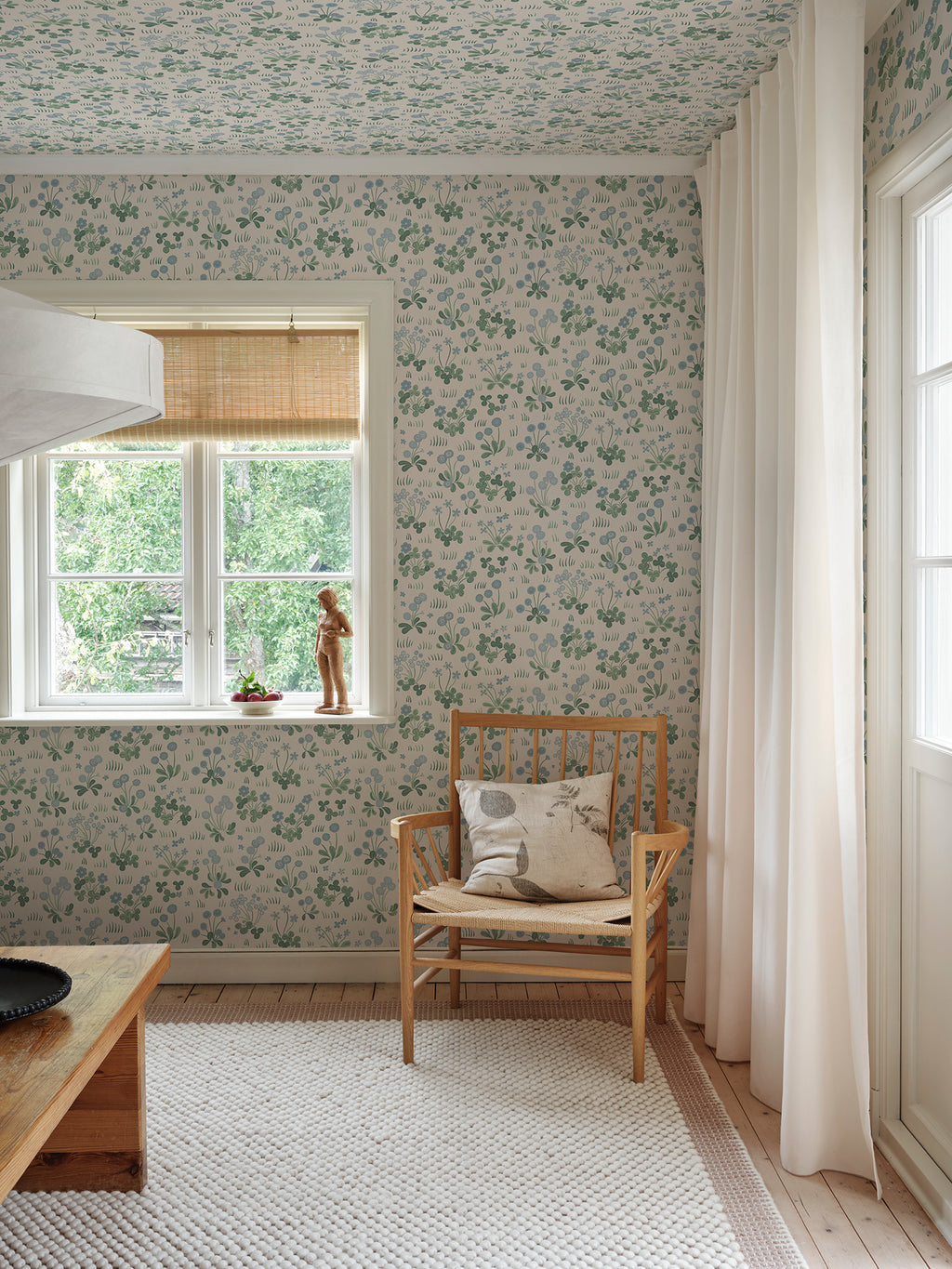 Bellis wallpaper by Sandberg in Misty Blue, styled on an interior wall
