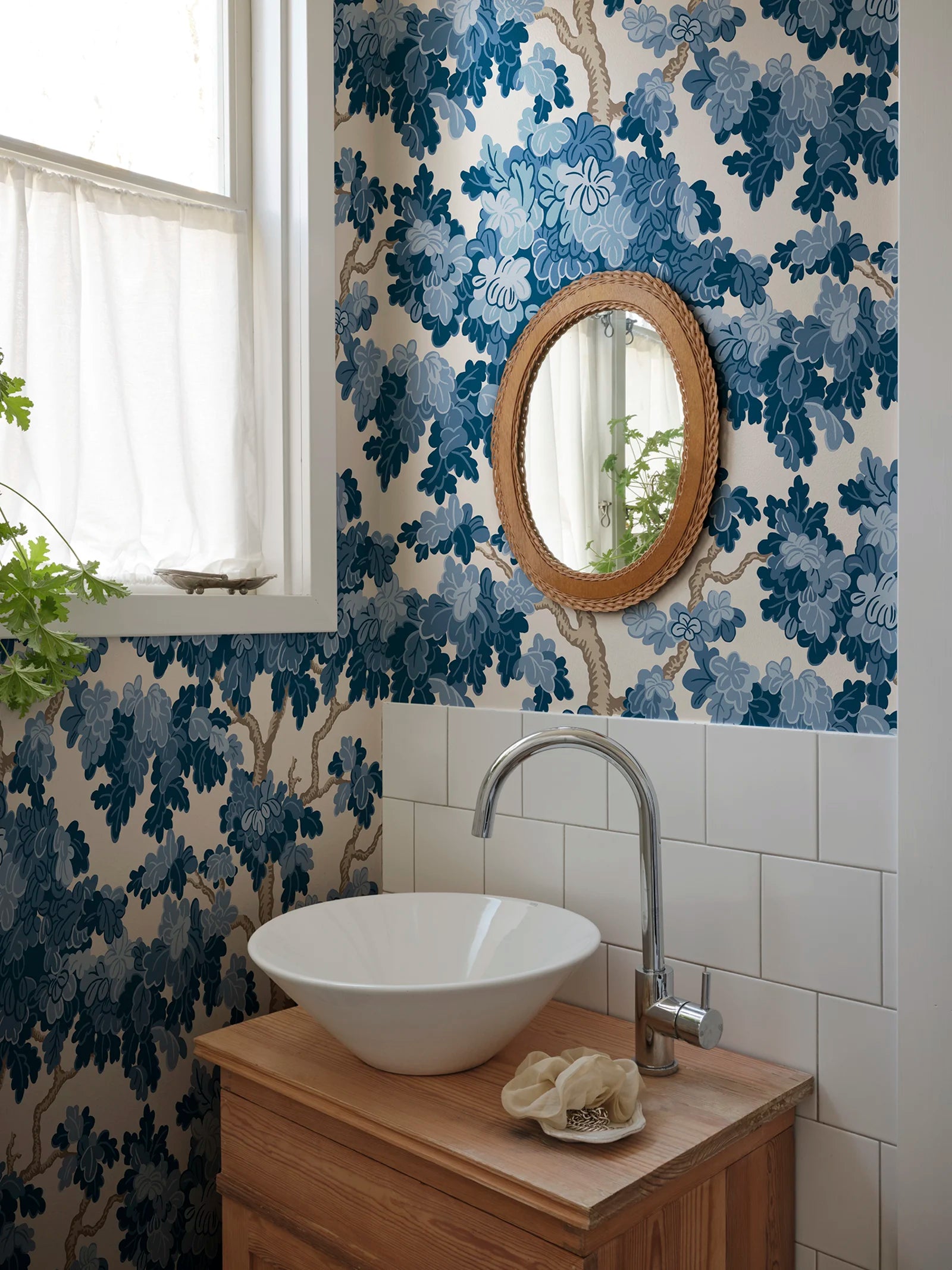 Eken wallpaper by Sandberg in deep blue, styled in a powder room with white vessel basin, timber vanity and rattan mirror