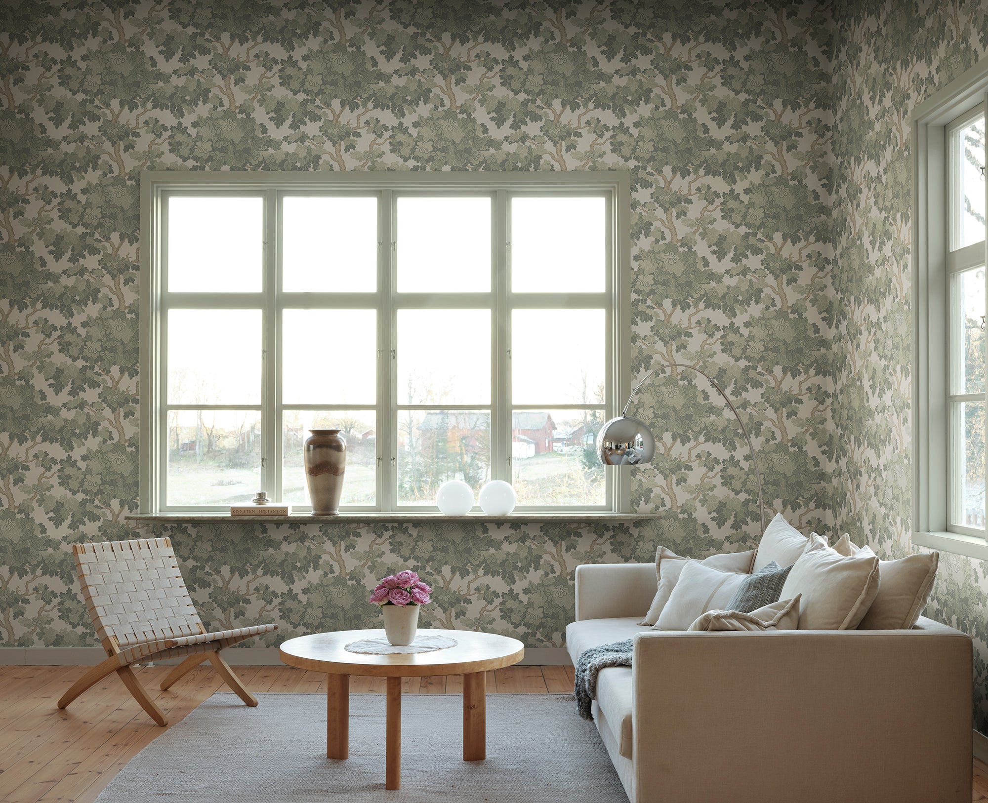 Eken wallpaper by Sandberg in sage green, styled in a living room around a large window with sofa, woven chair and arc lamp
