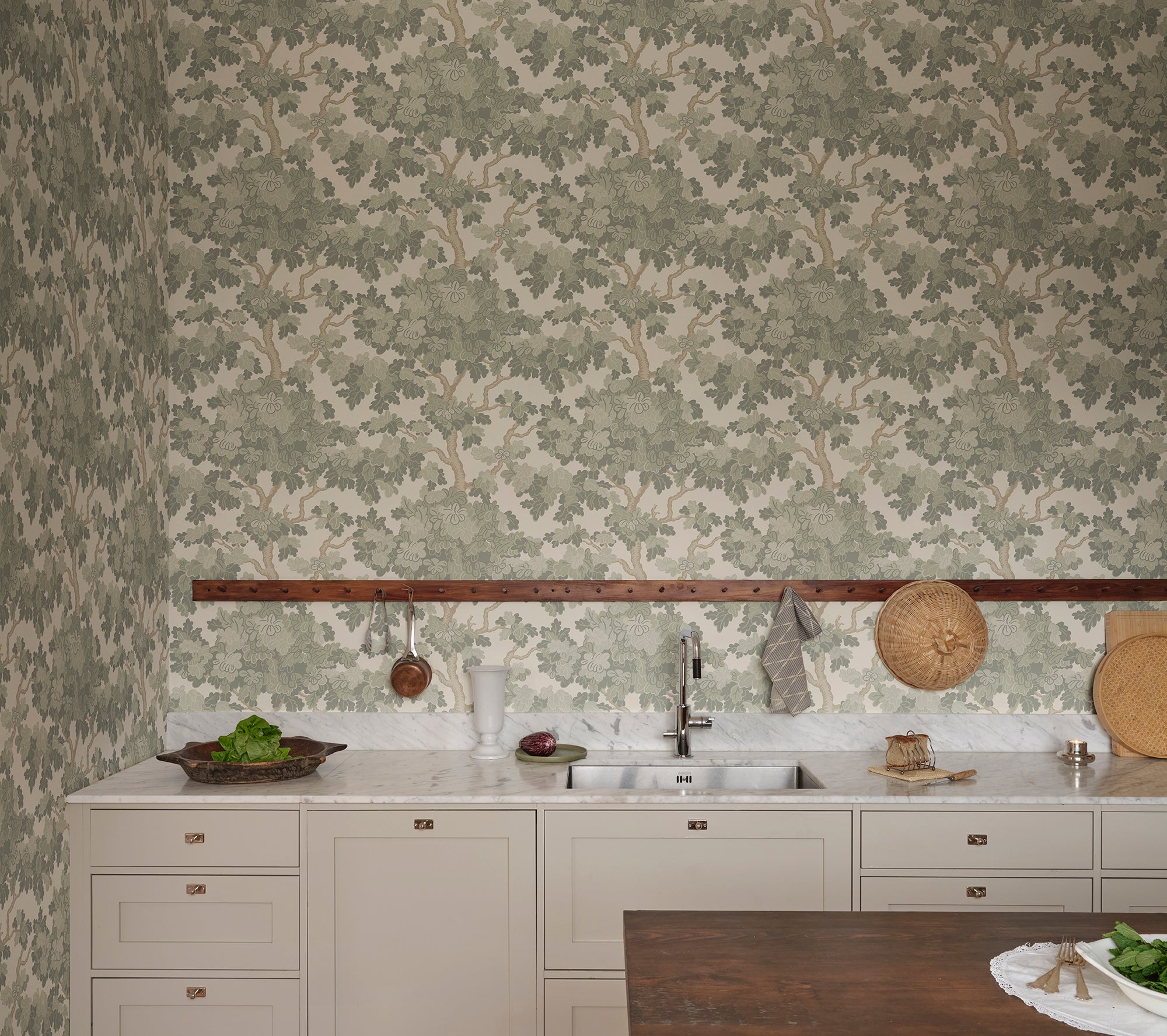 Eken wallpaper by Sandberg in sage green, styled as a kitchen wall above marble counter and pale cabinetry with hanging rail