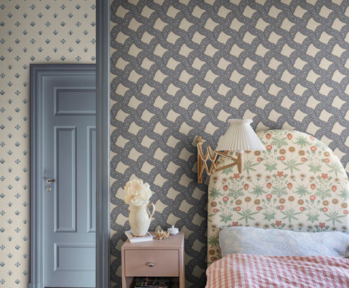 Annie wallpaper by Sandberg in navy styled in a bedroom behind a floral upholstered headboard with a pink nightstand and blue door