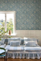 Rosa wallpaper by Sandberg above white panelling with a blue check sofa and window, blue floral-trellis pattern