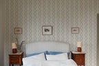 Emilion wallpaper by Sandberg in Blue behind a striped headboard in a calm bedroom with framed prints