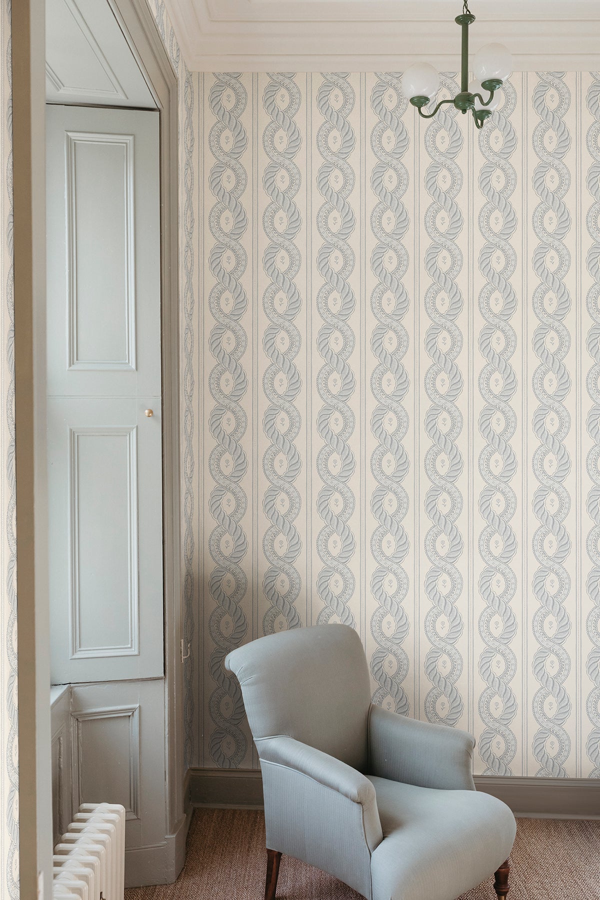 Emilion wallpaper by Sandberg in Blue in a corner with a grey armchair and green pendant light