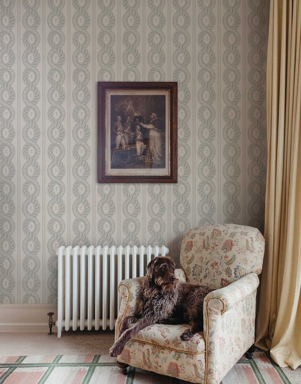 Emilion wallpaper by Sandberg in Green beside an armchair and radiator with a framed print