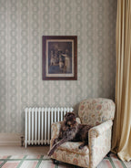 Emilion wallpaper by Sandberg in Green beside an armchair and radiator with a framed print