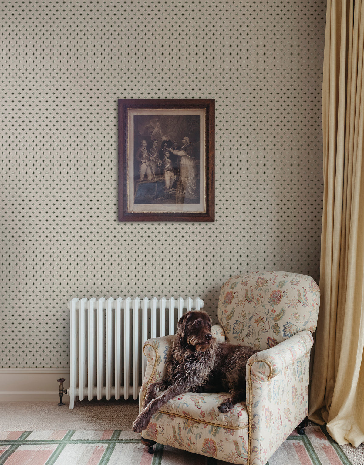Elise wallpaper by Sandberg in Green beside an armchair and radiator with a framed print