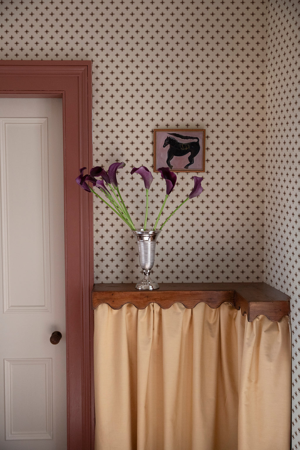 Elise wallpaper by Sandberg in Brown in a hallway with a pink-trimmed door and calla lilies