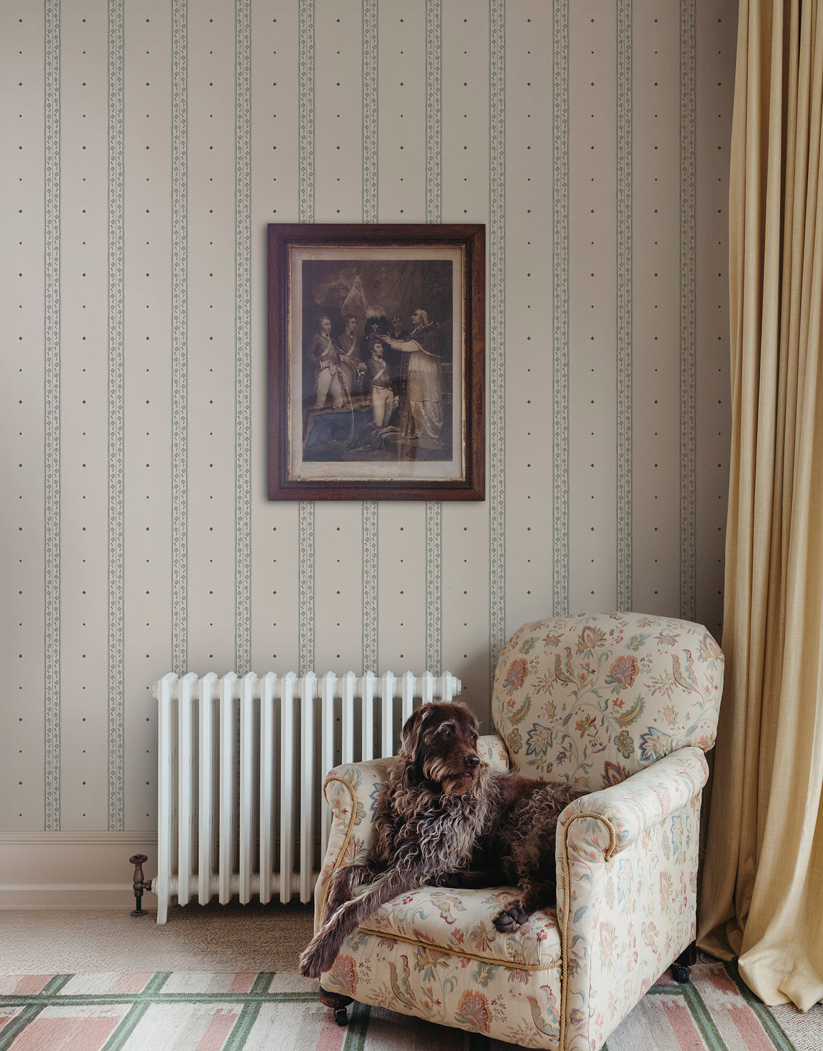 Austine wallpaper by Sandberg in Green beside an armchair and radiator with a framed print