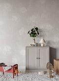 Poppy wallpaper by Sandberg in pale oatmeal, styled in a nursery behind a grey cabinet, red toddler bed and rattan chair