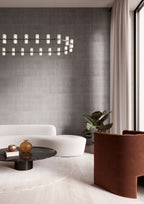 Katan Silk wallpaper by Arte in Grey – Mink in a living room with a white sofa and a rust armchair