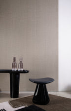 Lana wallpaper by Arte in Brown behind a black side table and stool