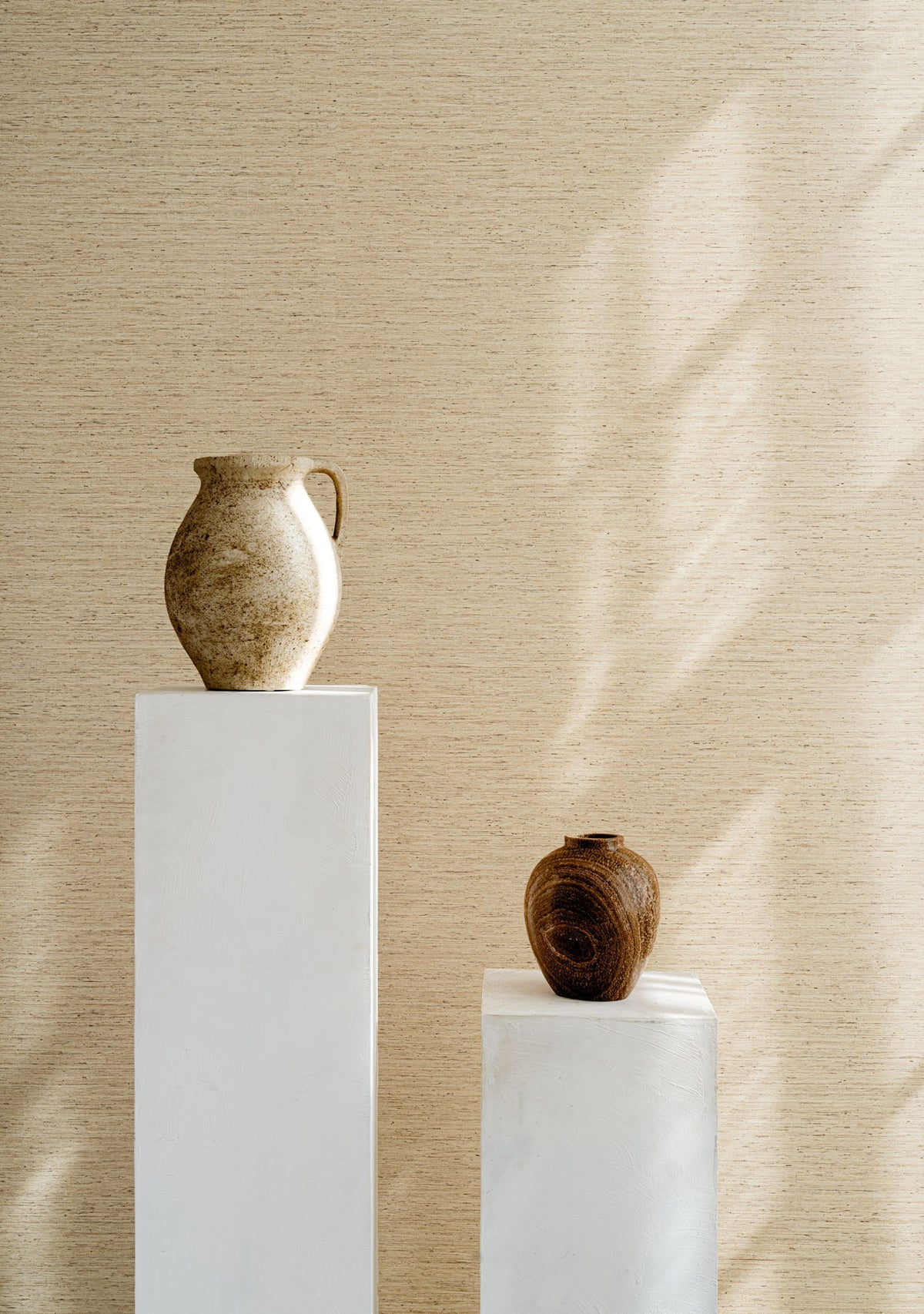 Motas wallpaper by Arte in Cream – Beach behind two vases on white plinths