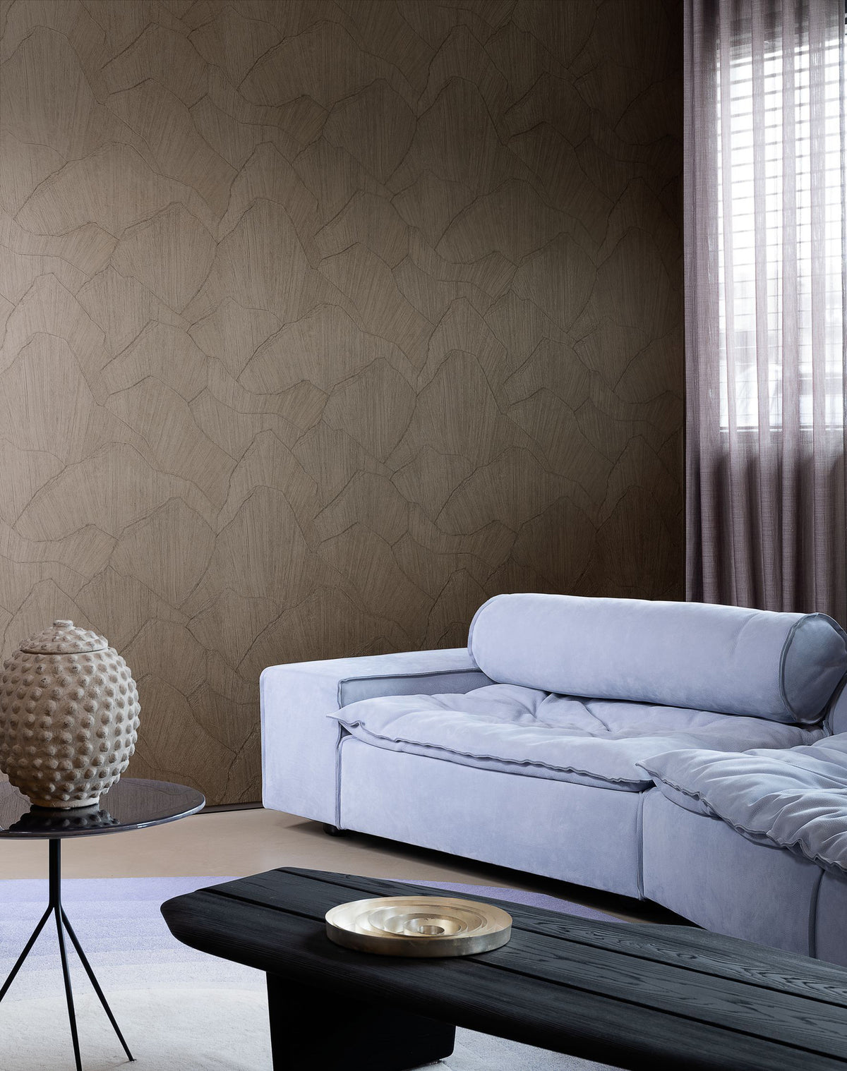 Shards wallpaper by Arte in Brown behind a lilac sofa and a black coffee table