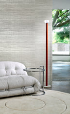Eri wallpaper by Arte in Grey – Pearl behind a low sofa and a tall red floor lamp