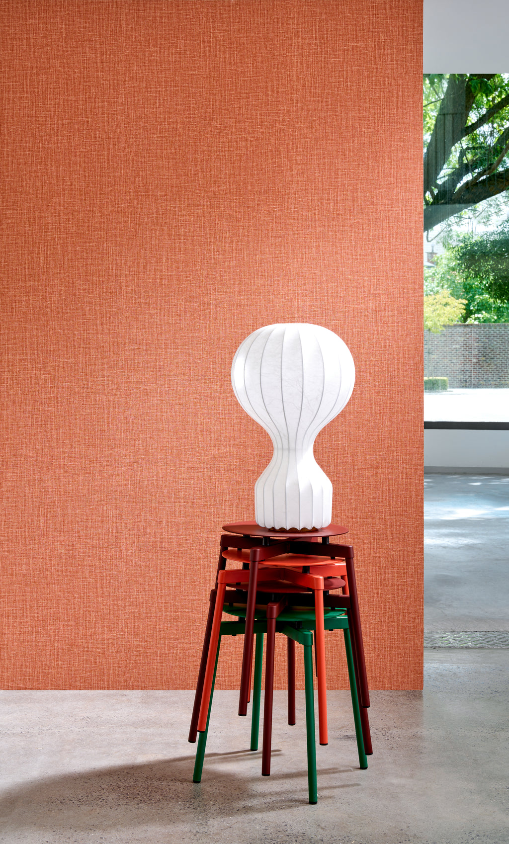 Gioco wallpaper by Arte in Orange behind a white globe lamp on a stack of stools