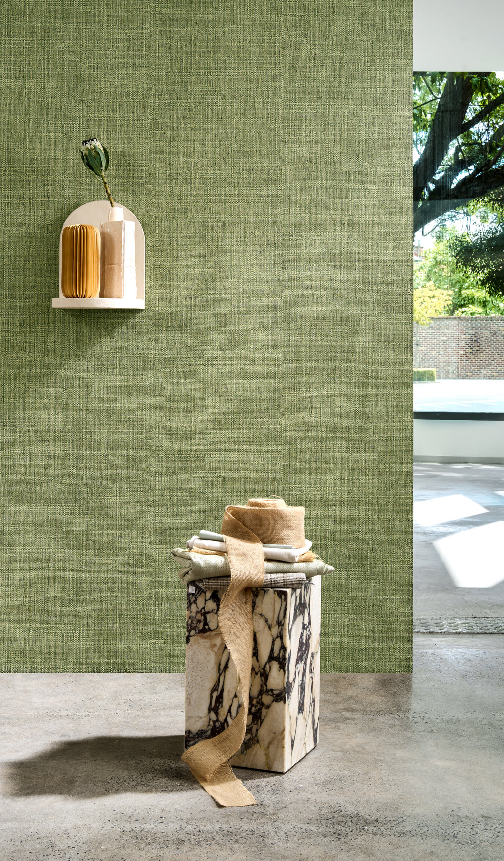 Nongo wallpaper by Arte in Green behind a plinth in a bright room