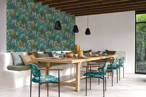 Belize wallpaper by Casamance in teal, a jungle print with leopards and palms styled in a dining room with a long timber table