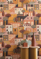Monterosso wallpaper by Casamance in sienna, a hillside village mural styled behind ochre plinths and ceramic vessels