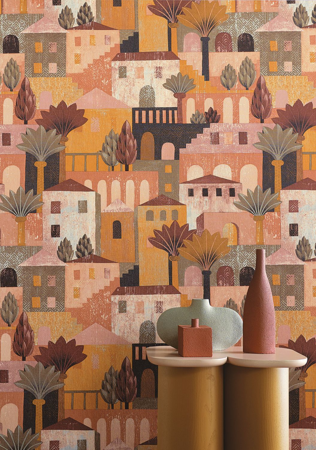 Monterosso wallpaper by Casamance in sienna, a hillside village mural styled behind ochre plinths and ceramic vessels