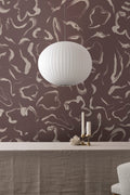 Aqueous wallpaper by Emma Hayes in pinot and gold, plum marbled swirls in a dining setting with candles