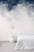 Bloom wallpaper by Emma Hayes in blue, soft watercolour petals cascading down a wall above a white linen bed