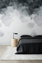 Bloom wallpaper by Emma Hayes in charcoal, watercolour petals above a bed with dark grey linen